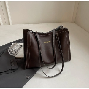Detail of dark brown tote bag featuring white contrast stitching and gold lettering