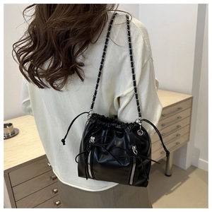 Détails du sac seau noir à cordon avec bandoulière chaîne argentée et nœuds en cuir