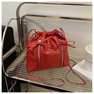 Détail du sac seau rouge avec coulisse, nœuds en cuir et bandoulière chaîne argent