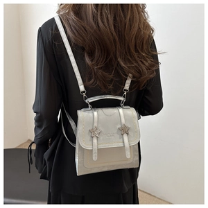 Close-up of a metallic silver mini backpack with star buckles and leather texture