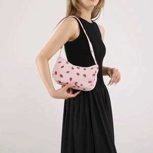 Sac sous le bras en velours côtelé rose à motif fraises porté sur robe noire