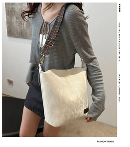 Close-up of retro white leather tote bag with a Bohemian embroidered wide strap