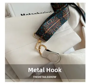 Close-up of golden hardware clasp and colorful ethnic pattern strap on white bag