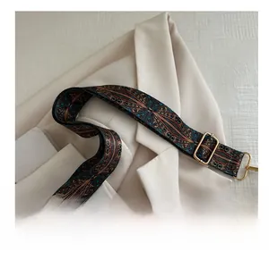 Detail of adjustable woven shoulder strap with ethnic pattern and gold metal hardware
