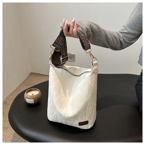 Detail of white bucket bag with ethnic printed strap and fashion tag on textured leather