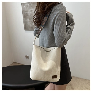 Beige pleated leather tote bag with vintage ethnic strap shown on a model's shoulder