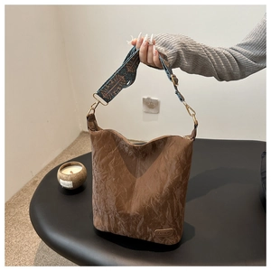 Close-up of brown bucket bag with vintage pleated texture and bohemian wide strap