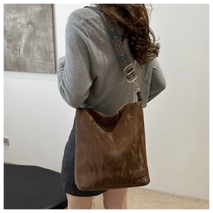 Detail of vintage brown leather tote bag with colorful ethnic style wide woven shoulder strap