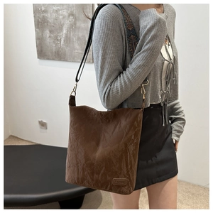 Detail of retro brown tote bag with wrinkled texture and ethnic style floral wide strap