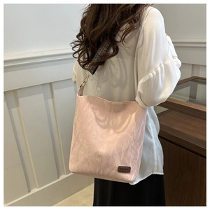 Detail of light pink pleated tote bag featuring vintage patterned wide strap and fashion tag