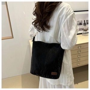 Detail of black nylon bucket bag with brown leather label and vintage woven shoulder strap