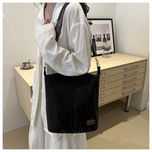 Detail of black pleated bucket bag with vintage jacquard strap and fashion leather tag