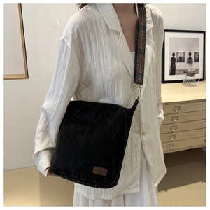 Detailed view of black wrinkled nylon shoulder bag with vintage printed wide strap on model