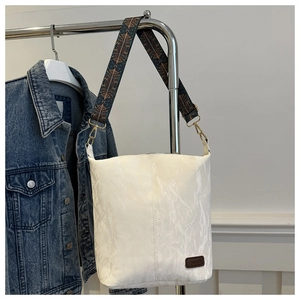 Detail of off-white marble textured tote bag with ethnic print strap and fashion label