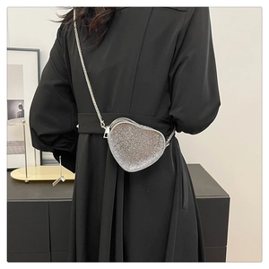 Close-up of heart-shaped mini bag with sparkling rhinestones and silver metal chain