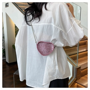 Detail of pink sequin heart-shaped mini bag with silver chain on white shirt