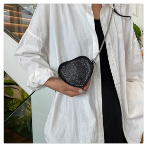 Close-up of black sequined heart-shaped crossbody bag with a slim silver chain strap