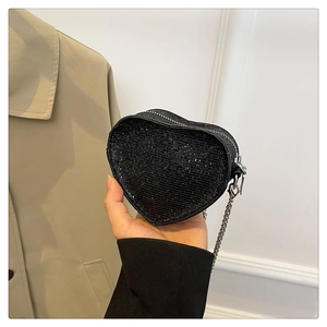 Detail of a mini heart-shaped crossbody bag with black sequins and a silver metal chain
