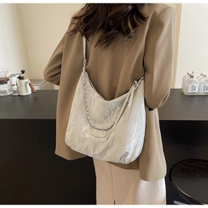 Detail of white wrinkled hobo bag with textured fabric and metallic chain strap