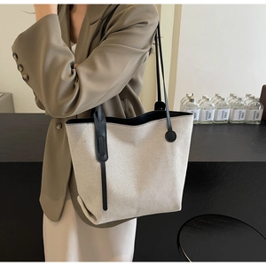 Große beige Nylon-Tragetasche mit schwarzen Riemen, getragen von einem Modell