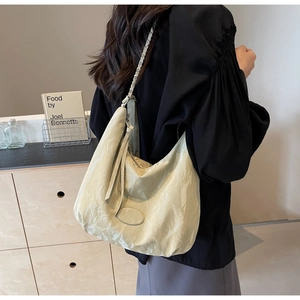 Detail of a creamy beige pleated PU leather hobo bag with a stylish chain strap