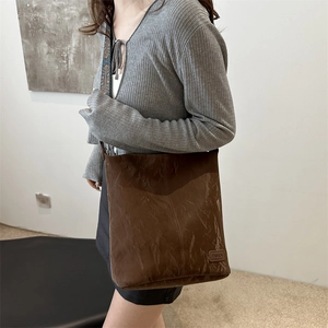 Retro dark brown tote bag with wrinkled texture and fashion label worn by a model