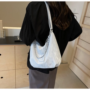 Detail of white wrinkled tote bag with silver chain strap shown on model shoulder