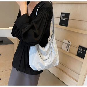Detail of light blue pleated PU leather hobo bag with silver chain and thin shoulder strap