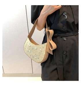 Detail of beige woven half-moon bag with floral embroidery and large bow decoration
