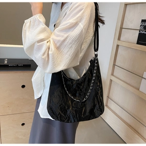 Close-up of black pleated leather tote bag with silver chain detail on female model