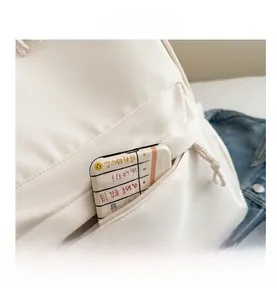Dettaglio dello zaino in nylon bianco con tasca frontale a zip e tiranti in corda