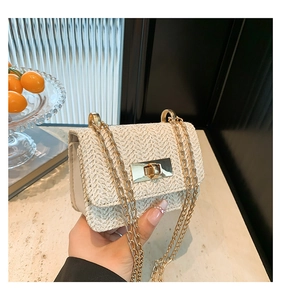 Dettaglio di una mini borsa intrecciata crema con chiusura dorata e tracolla a catena