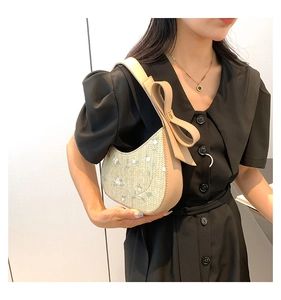 Detail of summer straw bag featuring delicate white flower embroidery and large bow strap
