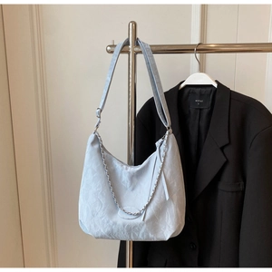 Detail of light blue pleated hobo bag featuring silver chain and adjustable shoulder strap