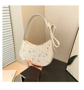 Detail of woven dumplings bag with floral embroidery and white ribbon handle