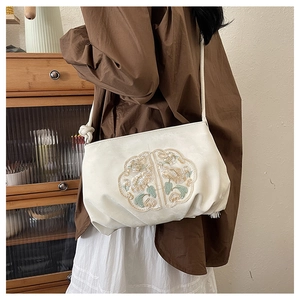 Detail of floral embroidery on a vintage style beige crossbody bag with knot decor