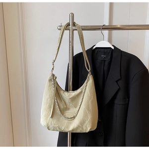 Detail of light beige tote bag with pleated texture and stylish silver chain accent