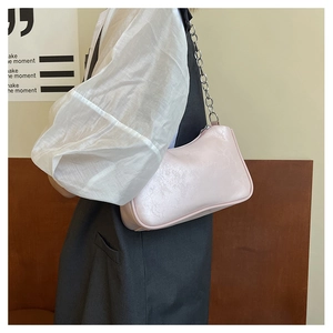 Close-up of light pink leather underarm bag with decorative silver metal chain strap