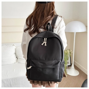 Vista posteriore di uno zaino nero minimalista con cerniere in corda intrecciata in casa