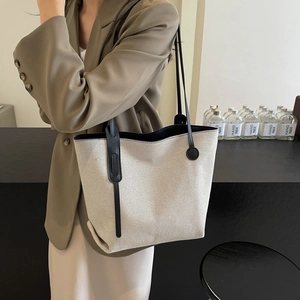 Minimalistische Tote Bag aus beigem Canvas und schwarzem Leder für das Büro am Model
