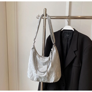 Detail of silver metallic hobo bag featuring pleated texture and silver chain strap