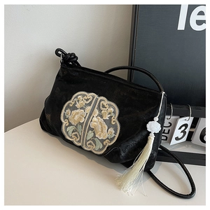 Detail of black velvet shoulder bag with floral embroidery and white lotus tassel charm
