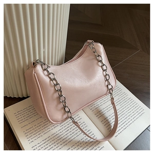 Detail of light pink shoulder bag with silver chain strap on vintage open books