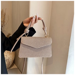 Détail d'un sac bandoulière beige tissé avec poignée en corde nouée et anneaux métalliques