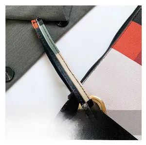 Detail of colorful checkered handbag strap with gold metal eyelet and textured fabric
