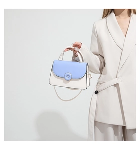 Détail du sac à bandoulière bicolore avec rabat bleu clair et corps blanc crème sur modèle
