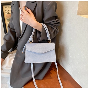 Détail d'un sac enveloppe bleu clair avec poignée nouée et anneaux dorés élégants
