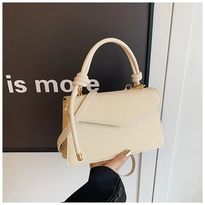 Détail du sac bandoulière tressé crème avec poignée en corde épaisse et boucles dorées