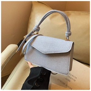 Detail of light blue woven handbag with gold ring hardware on a soft sofa