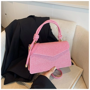 Détail du sac enveloppe à rayures roses et blanches avec poignée nouée sur canapé